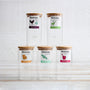 7 glass jars with various teapigs tea blend labels