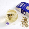 Glass cup of brewing calm tea with pack